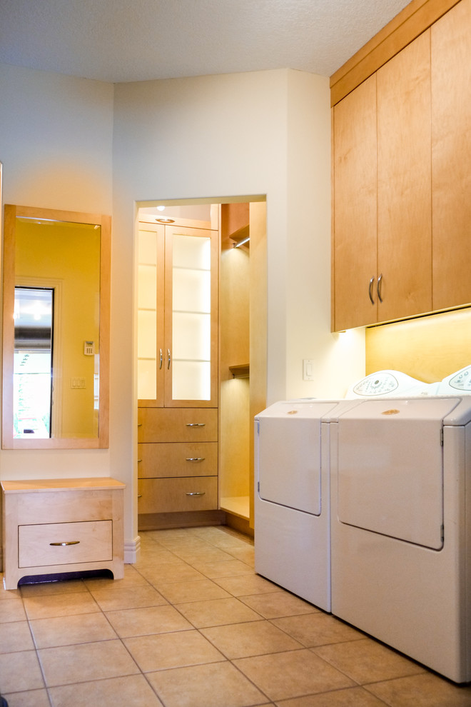 Idee per una lavanderia multiuso design di medie dimensioni con ante lisce, ante in legno chiaro, pareti beige, pavimento con piastrelle in ceramica e lavatrice e asciugatrice affiancate