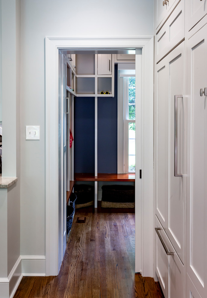 Klassisk inredning av ett litet flerfärgad parallellt flerfärgat grovkök, med en undermonterad diskho, luckor med infälld panel, grå skåp, marmorbänkskiva, blå väggar, mellanmörkt trägolv, en tvättmaskin och torktumlare bredvid varandra och brunt golv