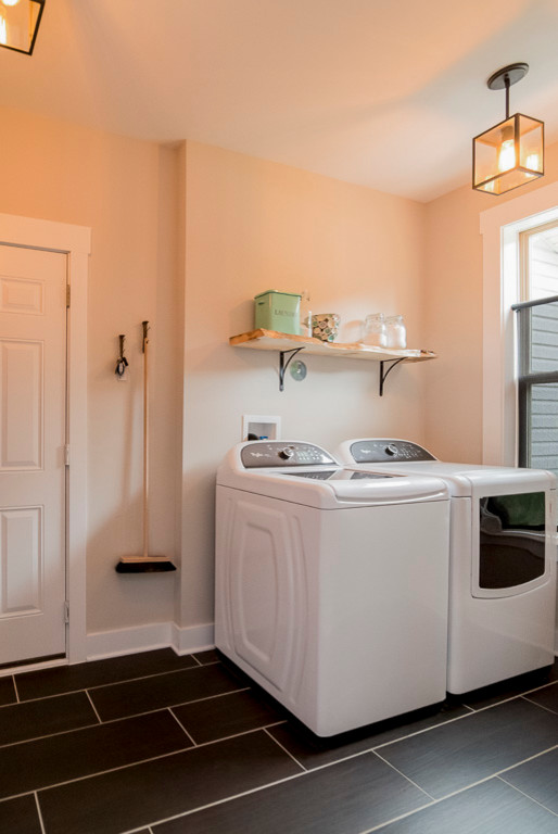 Modelo de lavadero de estilo de casa de campo con paredes grises, suelo de baldosas de cerámica y lavadora y secadora juntas
