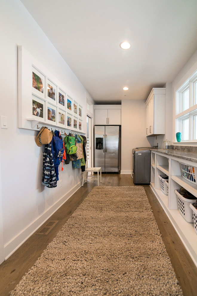 Example of a large cottage medium tone wood floor utility room design in Baltimore with open cabinets, white cabinets, laminate countertops, white walls and a side-by-side washer/dryer