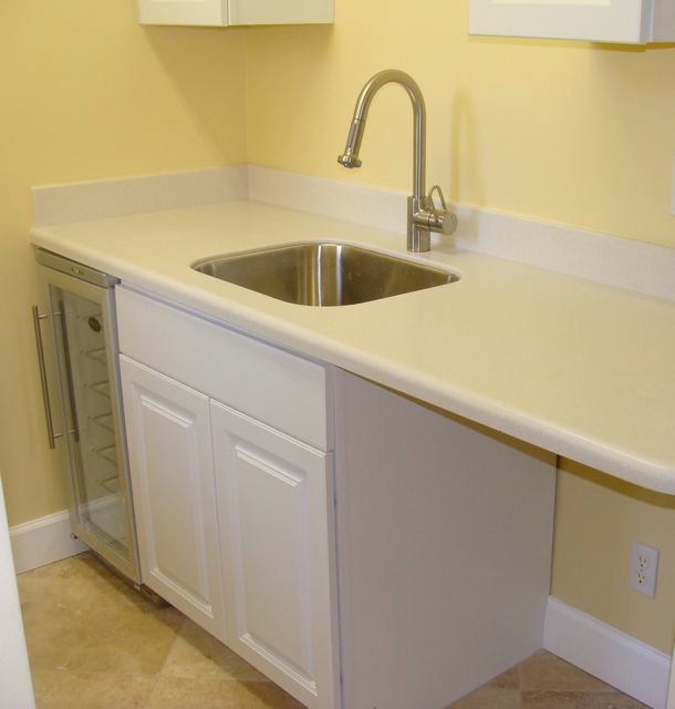 Photo of a medium sized traditional galley utility room in Jacksonville with a submerged sink, raised-panel cabinets, white cabinets, composite countertops, yellow walls, ceramic flooring and a side by side washer and dryer.