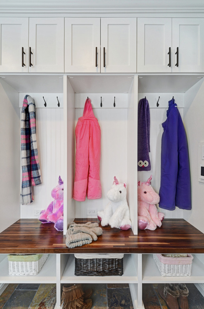 Immagine di una lavanderia multiuso tradizionale con ante con bugna sagomata, ante bianche, top in laminato e lavatrice e asciugatrice affiancate