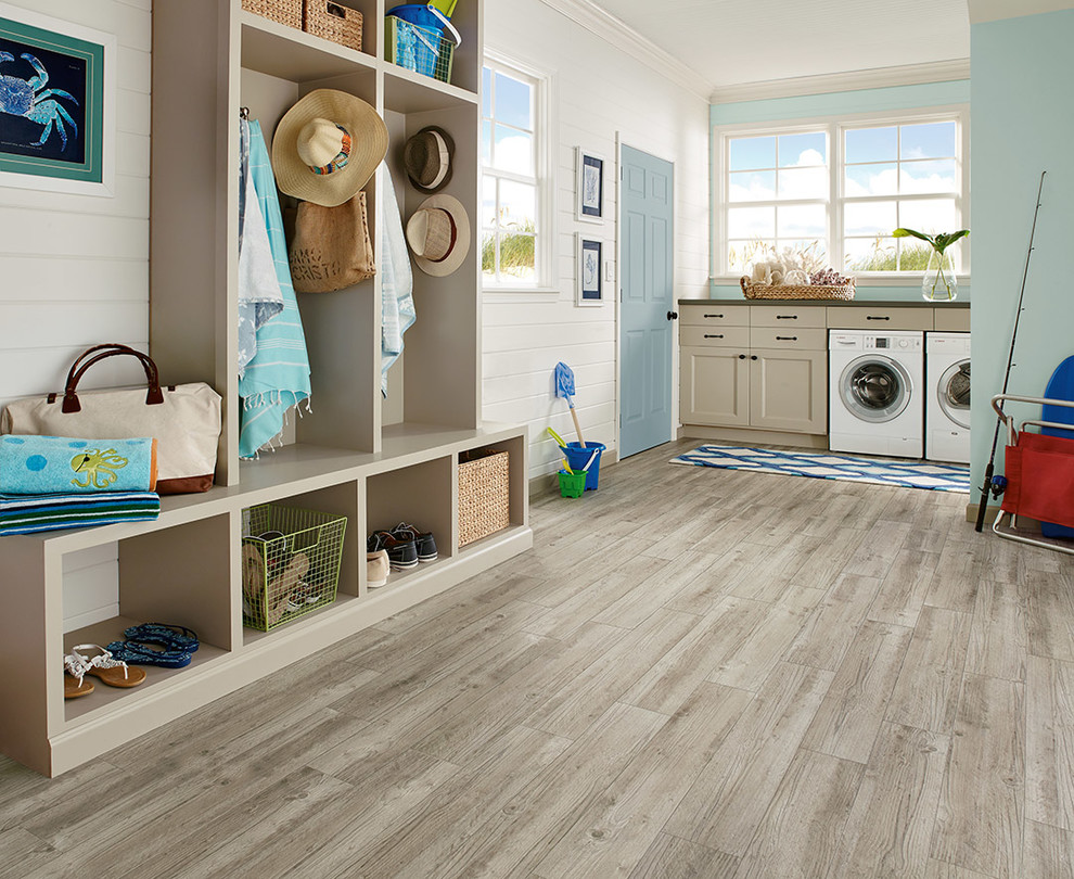Foto di una lavanderia costiera con ante lisce, ante beige, pareti blu, pavimento in vinile e lavatrice e asciugatrice affiancate