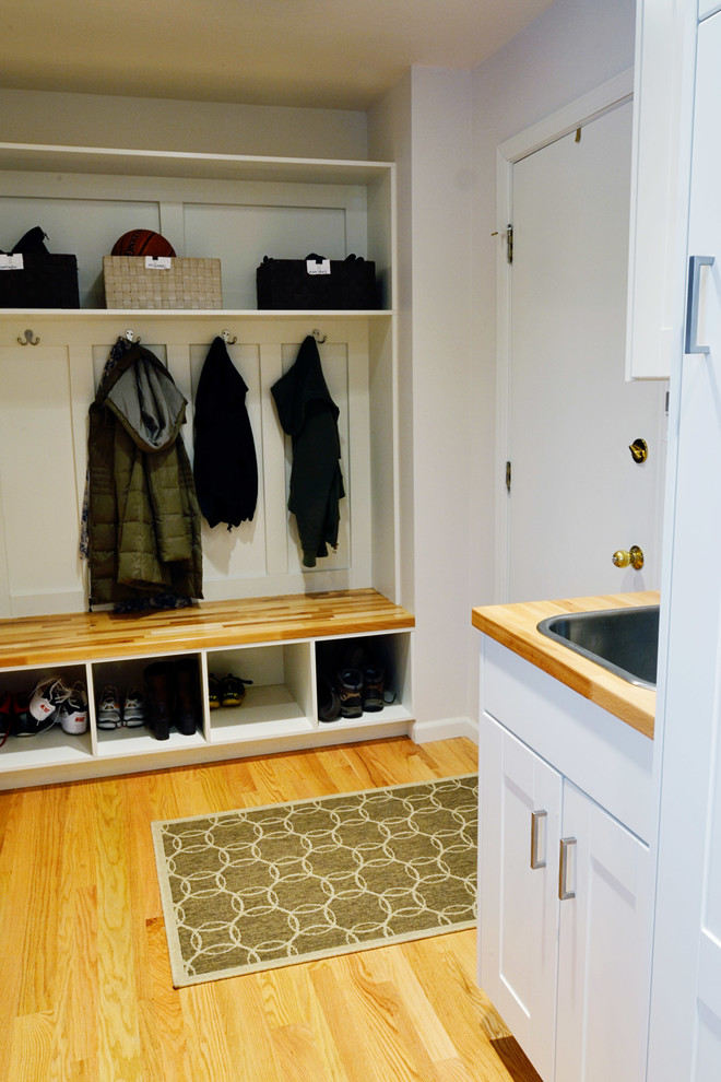 Example of a small transitional galley light wood floor utility room design in Other with a drop-in sink, shaker cabinets, white cabinets, wood countertops, gray walls and a stacked washer/dryer