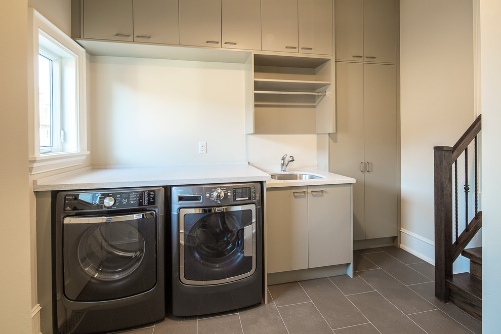 Medium sized contemporary single-wall utility room in Toronto with a single-bowl sink, flat-panel cabinets, grey cabinets, engineered stone countertops, porcelain flooring and a side by side washer and dryer.