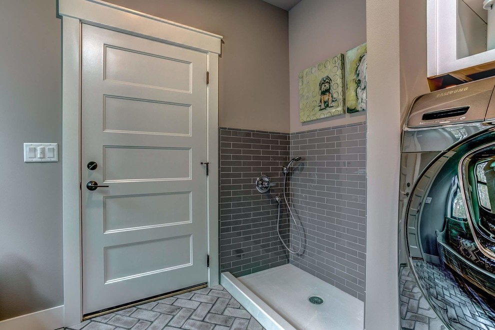 Immagine di una sala lavanderia country di medie dimensioni con pareti grigie, pavimento in mattoni, lavatrice e asciugatrice affiancate e pavimento grigio