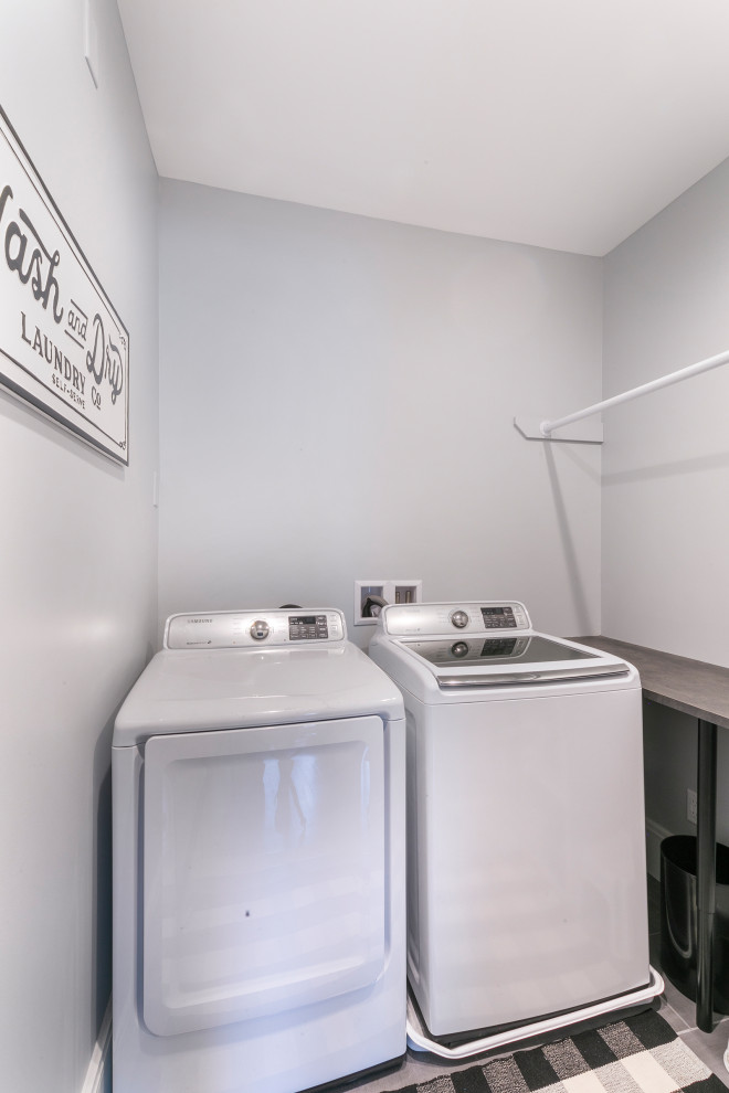 Foto di una piccola sala lavanderia tradizionale con top in laminato, pareti grigie, pavimento in gres porcellanato, lavatrice e asciugatrice affiancate, pavimento grigio e top grigio
