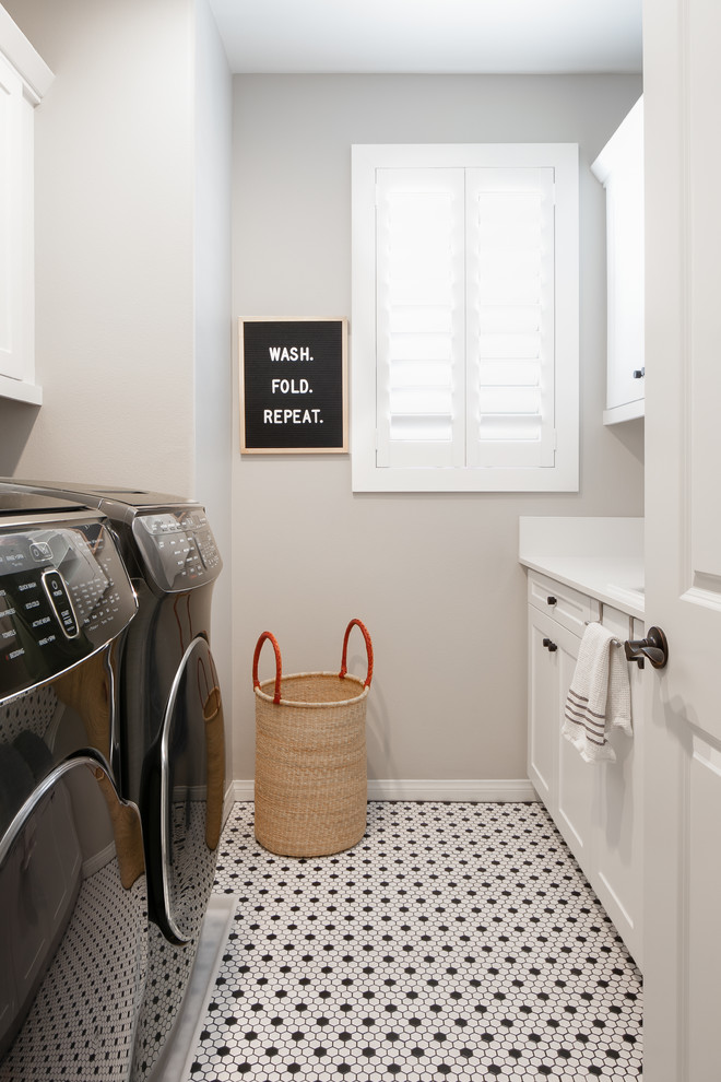 Zweizeilige Klassische Waschküche mit Schrankfronten im Shaker-Stil, weißen Schränken, grauer Wandfarbe, Waschmaschine und Trockner nebeneinander, buntem Boden und weißer Arbeitsplatte in Sonstige