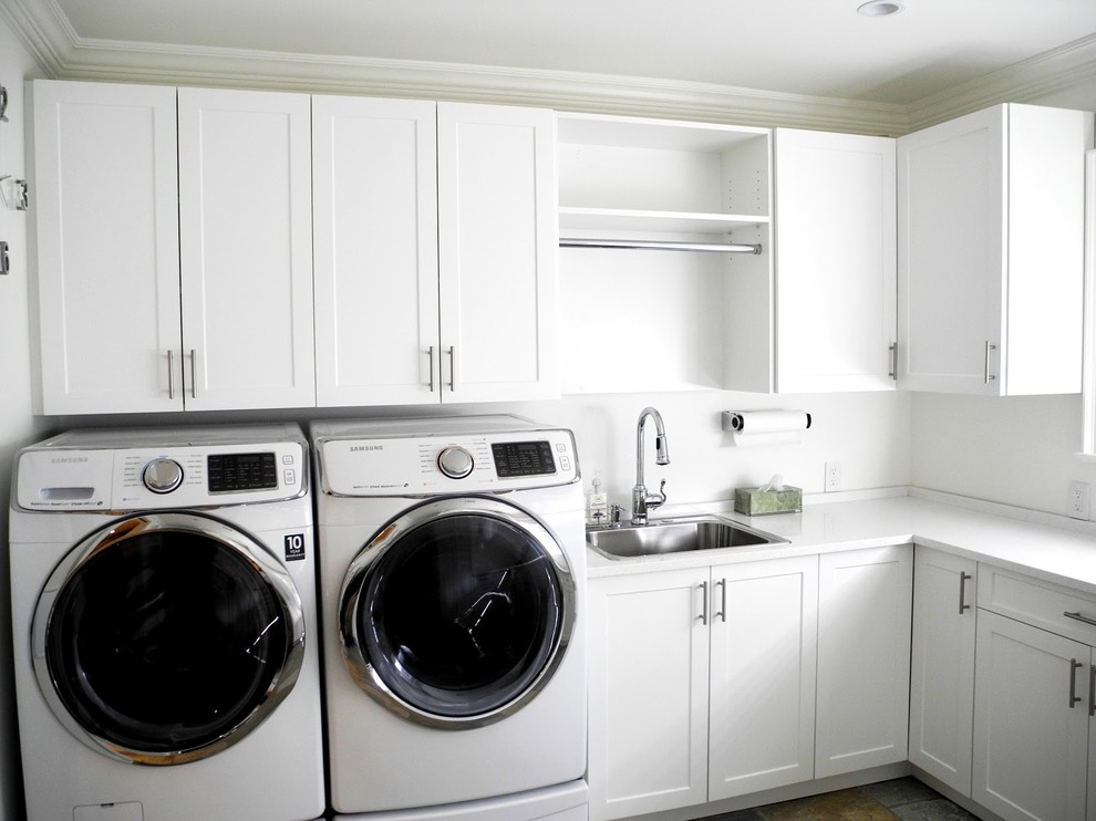 Foto på en mellanstor funkis vita u-formad tvättstuga, med en nedsänkt diskho, skåp i shakerstil, vita skåp, vita väggar och en tvättmaskin och torktumlare bredvid varandra