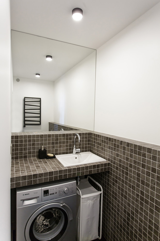 Exempel på en mellanstor industriell tvättstuga, med en nedsänkt diskho, klinkergolv i porslin, svart golv och vita väggar