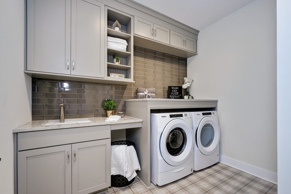 Immagine di una lavanderia multiuso classica con lavello sottopiano, ante in stile shaker, ante grigie, pareti beige, lavatrice e asciugatrice affiancate, pavimento multicolore e top grigio