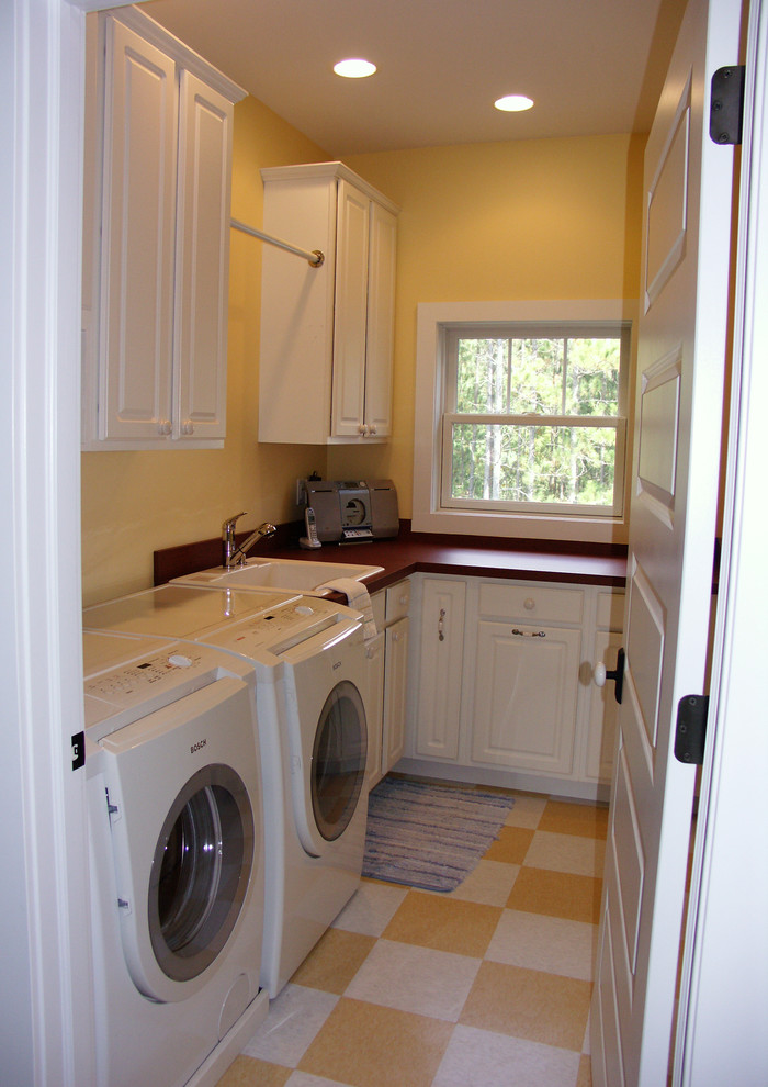 Inspiration för en mellanstor amerikansk l-formad tvättstuga enbart för tvätt, med en nedsänkt diskho, skåp i shakerstil, vita skåp, bänkskiva i koppar, gula väggar, klinkergolv i keramik och en tvättmaskin och torktumlare bredvid varandra