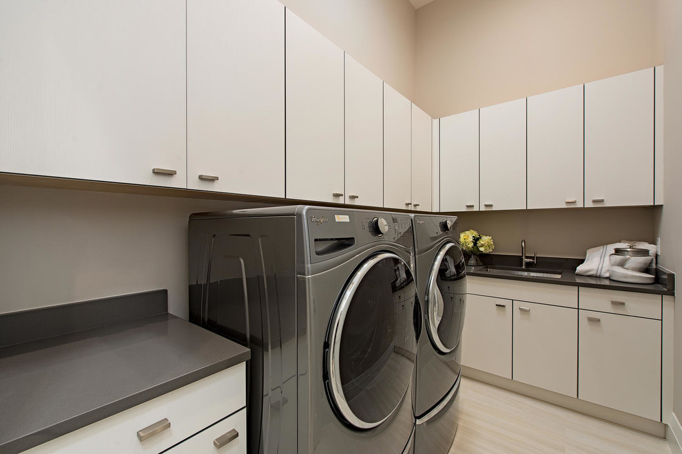 Inspiration for a medium sized contemporary l-shaped separated utility room in Miami with a single-bowl sink, flat-panel cabinets, engineered stone countertops, grey walls, porcelain flooring and a side by side washer and dryer.