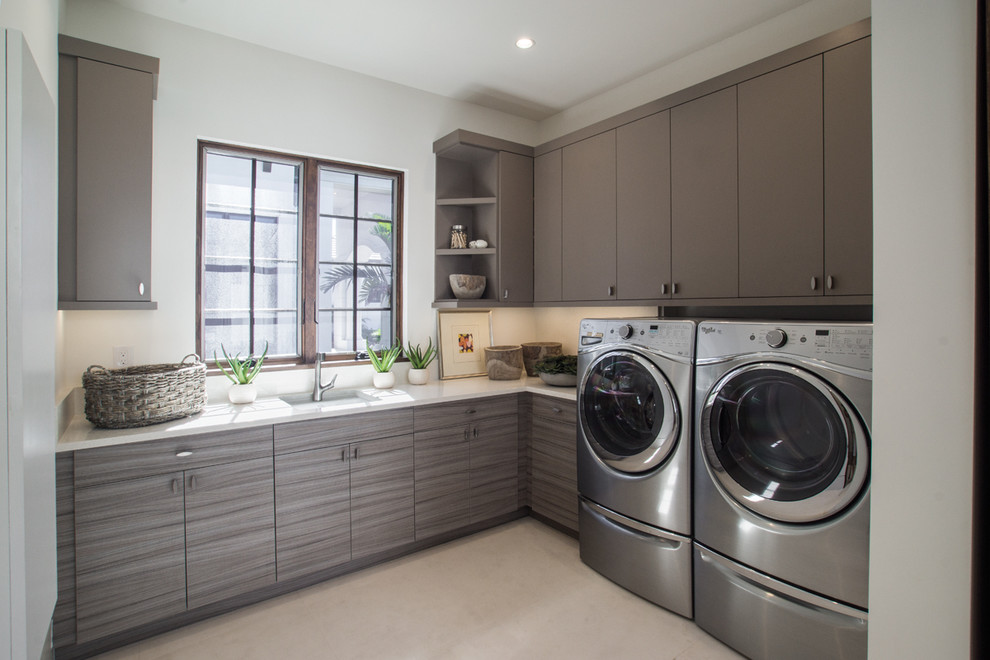 Immagine di una grande lavanderia design con ante lisce, ante grigie, top in quarzo composito e lavatrice e asciugatrice affiancate