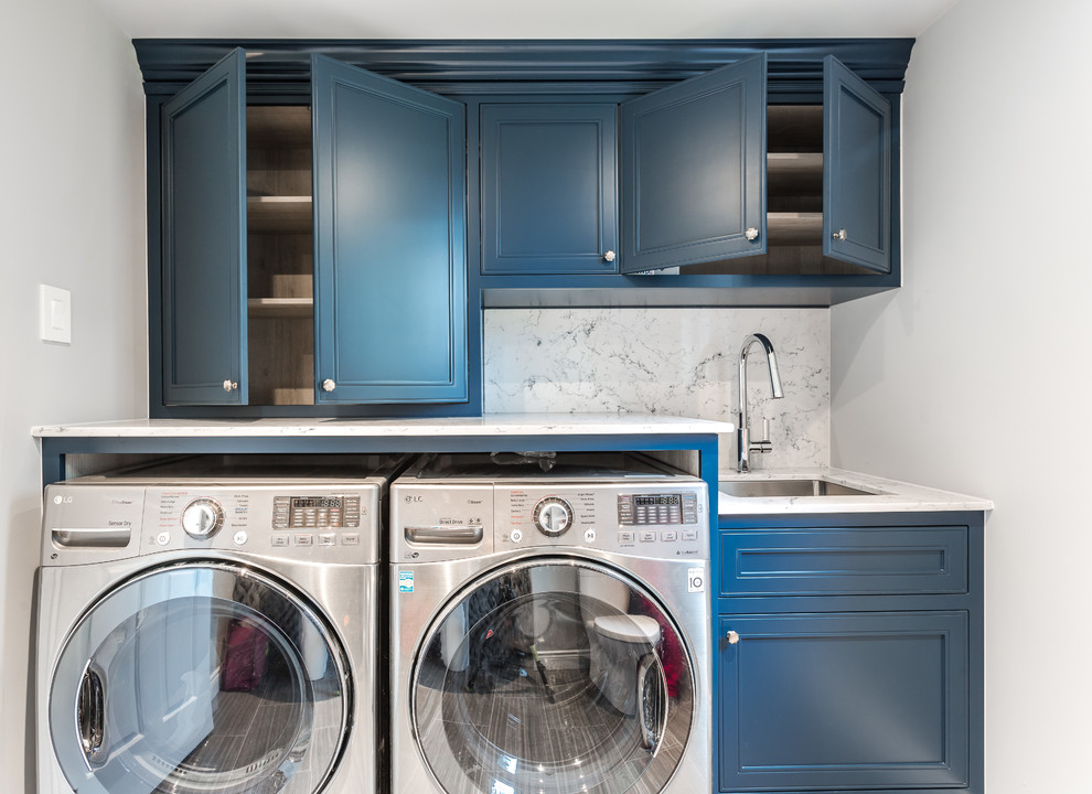 Einzeilige, Kleine Klassische Waschküche mit Unterbauwaschbecken, Kassettenfronten, blauen Schränken, Quarzwerkstein-Arbeitsplatte, weißer Wandfarbe, Keramikboden, Waschmaschine und Trockner nebeneinander, grauem Boden und grauer Arbeitsplatte in Montreal