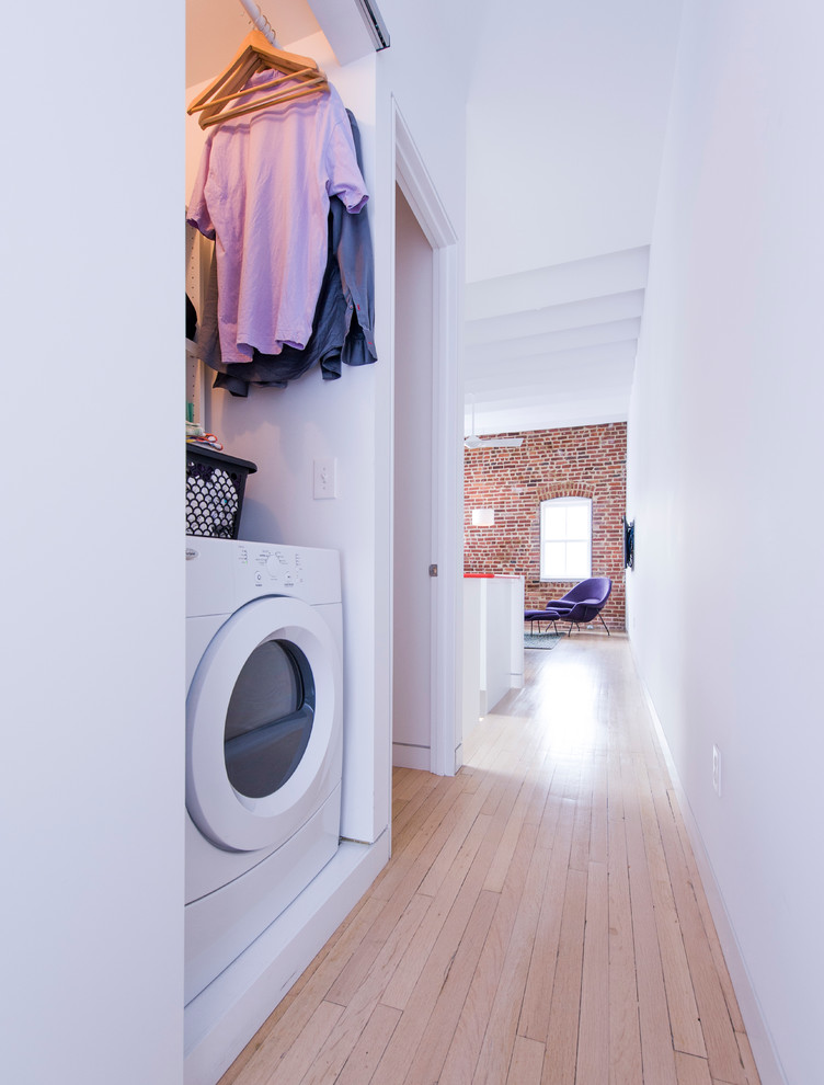 Skandinavischer Hauswirtschaftsraum mit Waschmaschinenschrank, weißer Wandfarbe, hellem Holzboden und Waschmaschine und Trockner nebeneinander in Washington, D.C.