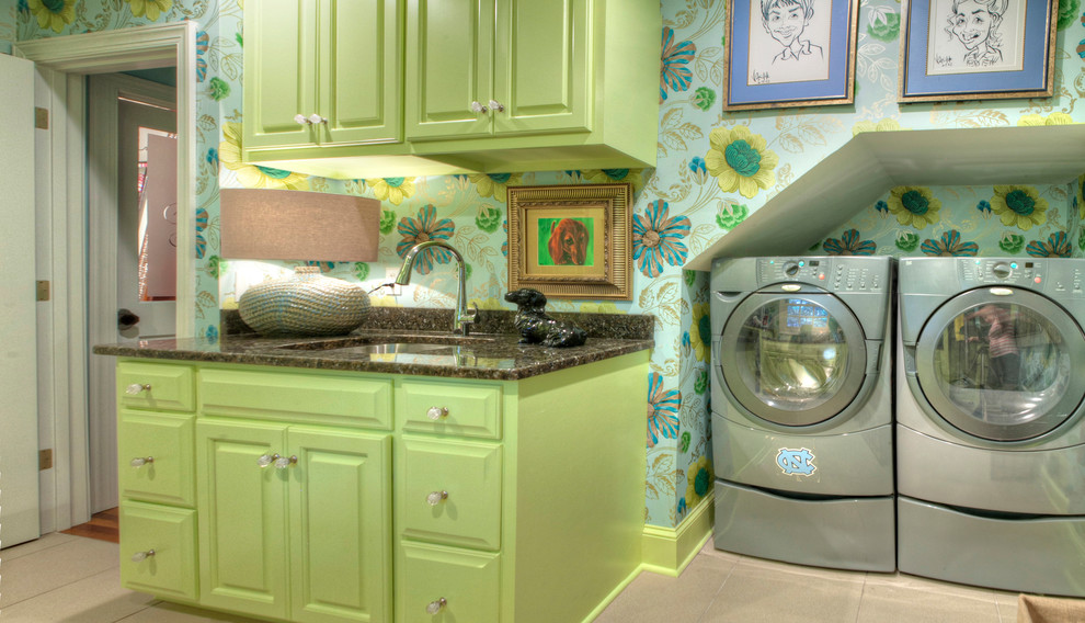 Inredning av en modern stor parallell tvättstuga enbart för tvätt, med en undermonterad diskho, luckor med upphöjd panel, gröna skåp, granitbänkskiva, flerfärgade väggar, klinkergolv i keramik och en tvättmaskin och torktumlare bredvid varandra
