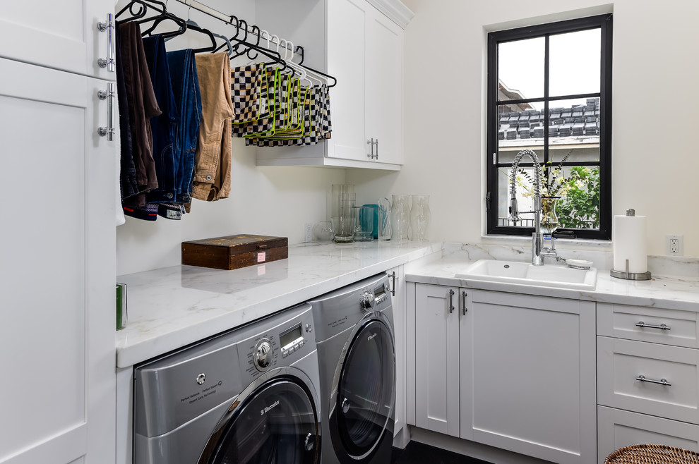 Example of a small transitional l-shaped dark wood floor and brown floor dedicated laundry room design in Miami with a drop-in sink, shaker cabinets, white cabinets, marble countertops, white walls, a side-by-side washer/dryer and white countertops