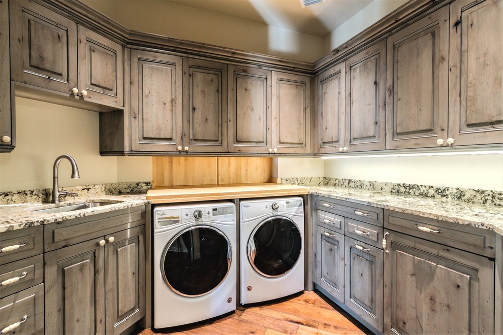 Large mediterranean u-shaped separated utility room in Miami with a submerged sink, raised-panel cabinets, medium wood cabinets, granite worktops, green walls, medium hardwood flooring, a side by side washer and dryer and multicoloured worktops.