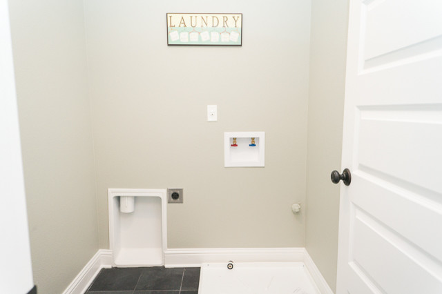 Foto på en mellanstor amerikansk linjär tvättstuga enbart för tvätt, med beige väggar, skiffergolv och en tvättmaskin och torktumlare bredvid varandra
