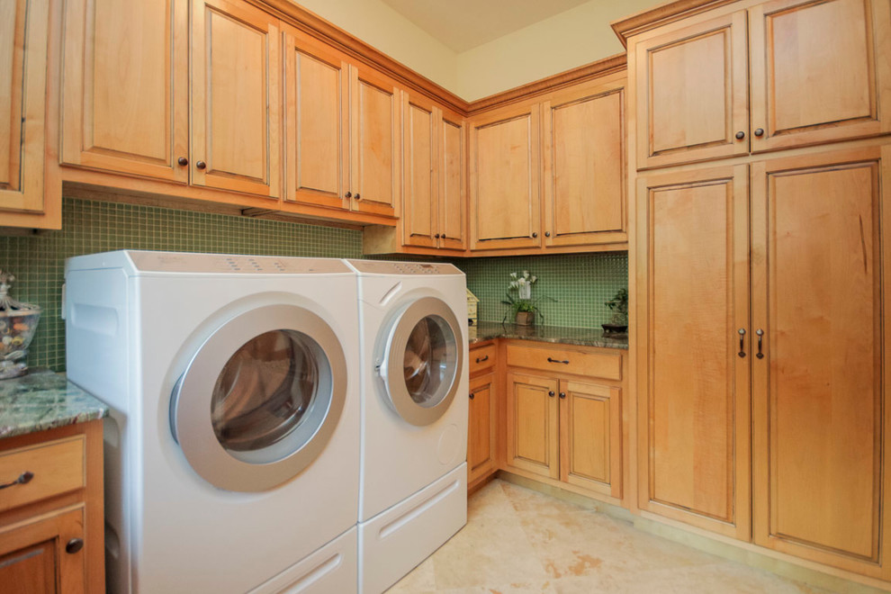 Idéer för stora vintage u-formade tvättstugor enbart för tvätt, med en undermonterad diskho, luckor med upphöjd panel, marmorbänkskiva, kalkstensgolv, en tvättmaskin och torktumlare bredvid varandra, skåp i mellenmörkt trä och beige väggar