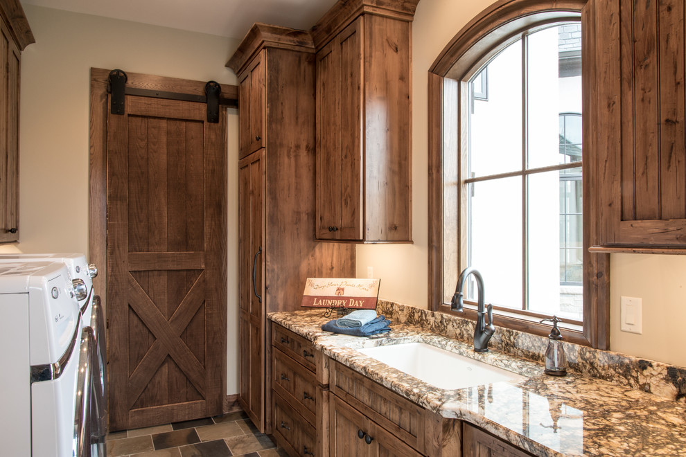 This is an example of a rustic utility room in St Louis with a submerged sink, shaker cabinets, granite worktops, beige walls, slate flooring, a side by side washer and dryer and dark wood cabinets.