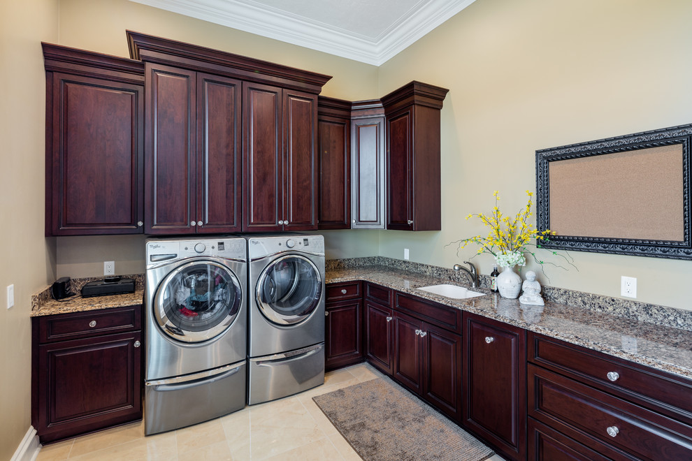 Photo of a large traditional utility room in Other with a submerged sink, raised-panel cabinets, dark wood cabinets, engineered stone countertops, yellow walls and a side by side washer and dryer.