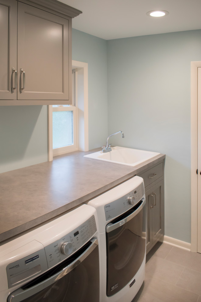 Small classic galley separated utility room in Other with an utility sink, recessed-panel cabinets, grey cabinets, laminate countertops, blue walls, ceramic flooring, an integrated washer and dryer, beige floors and grey worktops.