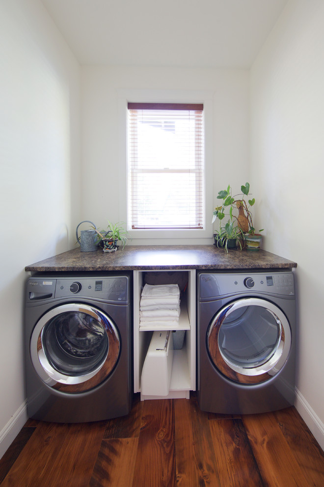 バンクーバーにある小さなラスティックスタイルのおしゃれな洗濯室 (ll型、白いキャビネット、ラミネートカウンター、白い壁、無垢フローリング、左右配置の洗濯機・乾燥機) の写真