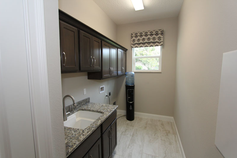 Bild på en mellanstor funkis grå parallell grått tvättstuga enbart för tvätt, med en rustik diskho, luckor med infälld panel, skåp i mörkt trä, granitbänkskiva, grå väggar, klinkergolv i keramik och beiget golv