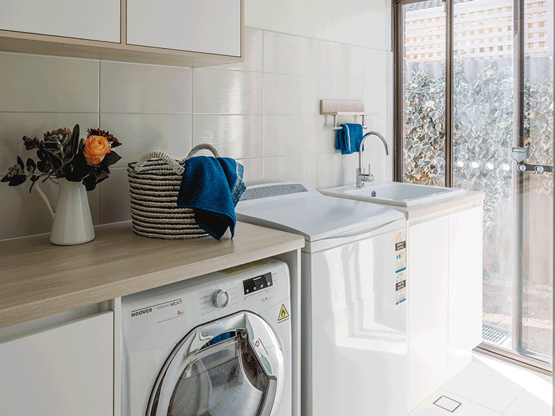 Inspiration för mellanstora moderna l-formade tvättstugor enbart för tvätt, med en undermonterad diskho, släta luckor, vita skåp, laminatbänkskiva, gröna väggar, klinkergolv i keramik, en tvättpelare och vitt golv