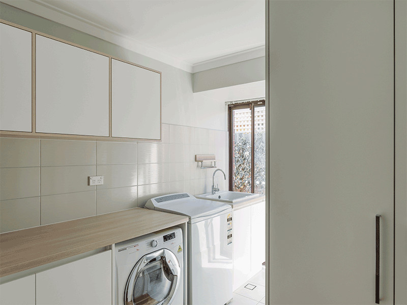 Inspiration för en mellanstor funkis l-formad tvättstuga enbart för tvätt, med en undermonterad diskho, släta luckor, vita skåp, laminatbänkskiva, gröna väggar, klinkergolv i keramik, en tvättpelare och vitt golv