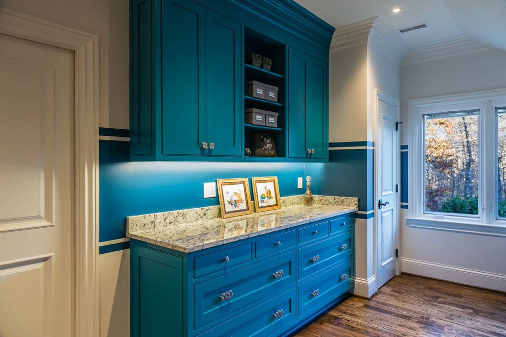 Immagine di una grande sala lavanderia contemporanea con lavello sottopiano, ante blu, top in granito, pareti blu, pavimento in legno massello medio, lavatrice e asciugatrice affiancate e ante a filo
