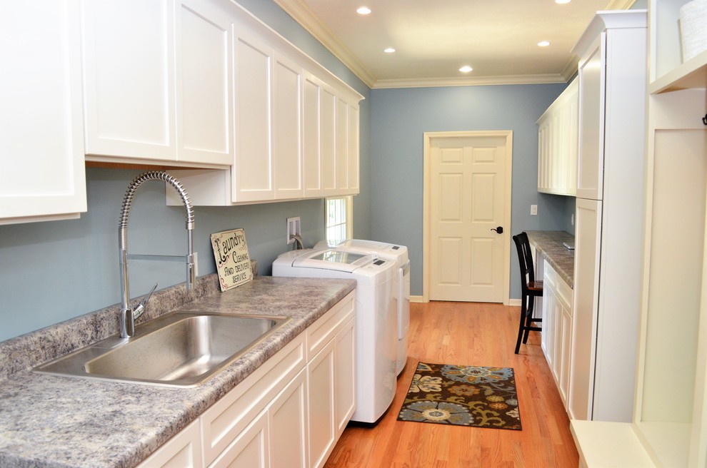 This is an example of a medium sized rural galley separated utility room in Other with a single-bowl sink, recessed-panel cabinets, white cabinets, laminate countertops, blue walls, a side by side washer and dryer, light hardwood flooring, brown floors and grey worktops.