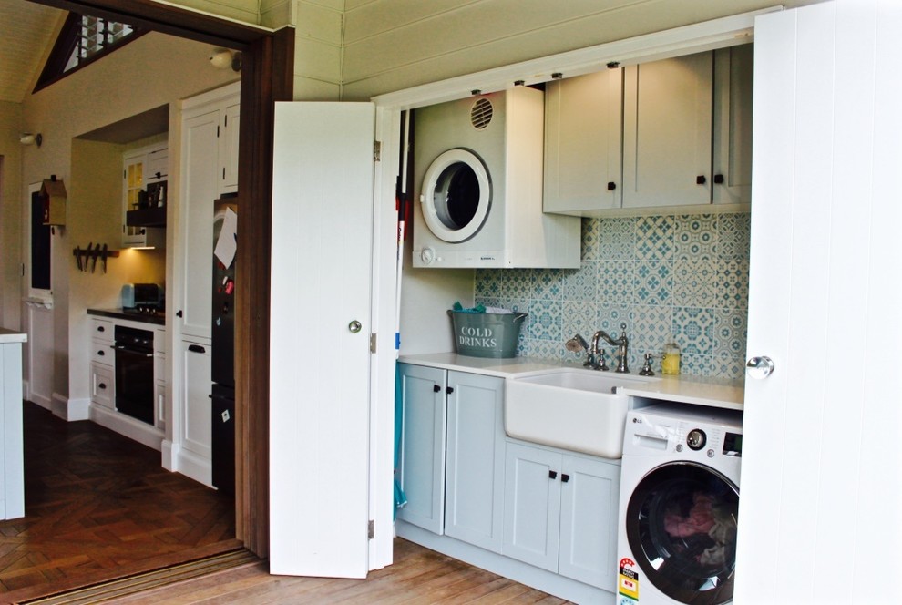 Einzeiliger Moderner Hauswirtschaftsraum mit Waschmaschinenschrank, integriertem Waschbecken, Schrankfronten im Shaker-Stil, blauen Schränken und blauer Wandfarbe in Brisbane