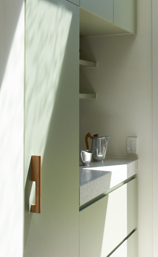 На фото: параллельная универсальная комната в современном стиле с одинарной мойкой, зелеными фасадами, столешницей терраццо, белыми стенами, полом из керамической плитки, с сушильной машиной на стиральной машине, серым полом и серой столешницей