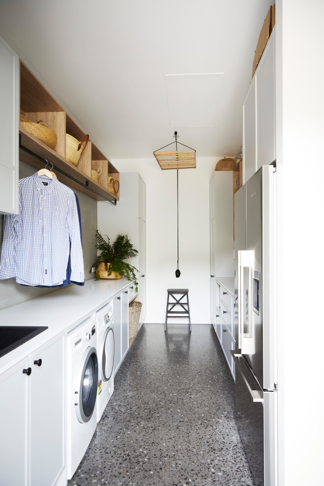 Medium sized contemporary galley utility room in Other with a built-in sink, shaker cabinets, engineered stone countertops, grey splashback, glass tiled splashback, white walls, concrete flooring, a side by side washer and dryer, white worktops, turquoise cabinets and grey floors.