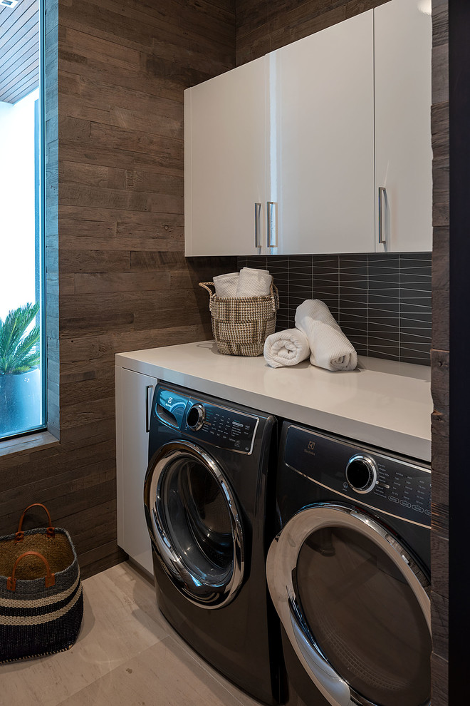 Kleiner Moderner Hauswirtschaftsraum mit Waschmaschinenschrank, brauner Wandfarbe, Waschmaschine und Trockner nebeneinander, beigem Boden und weißer Arbeitsplatte in San Diego