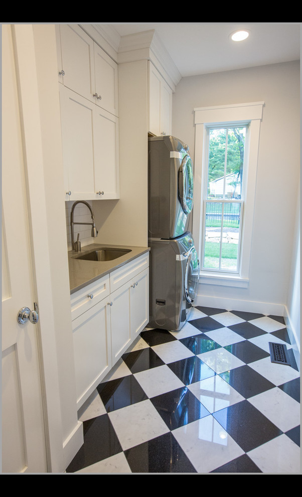 Inspiration for a small transitional single-wall porcelain tile dedicated laundry room remodel in New York with an undermount sink, shaker cabinets, white cabinets, quartz countertops, gray walls and a stacked washer/dryer