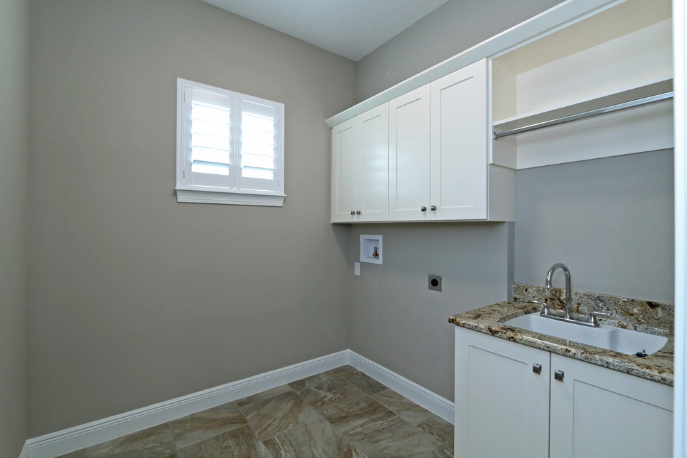 Photo of a medium sized traditional separated utility room in Orlando with a submerged sink, recessed-panel cabinets, white cabinets, ceramic flooring, a side by side washer and dryer, granite worktops and grey walls.