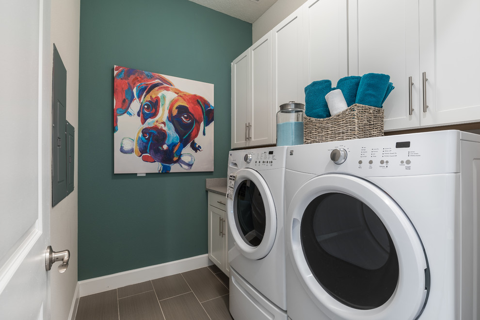 Ispirazione per una sala lavanderia con ante bianche, pareti verdi, lavatrice e asciugatrice affiancate, pavimento beige e top beige