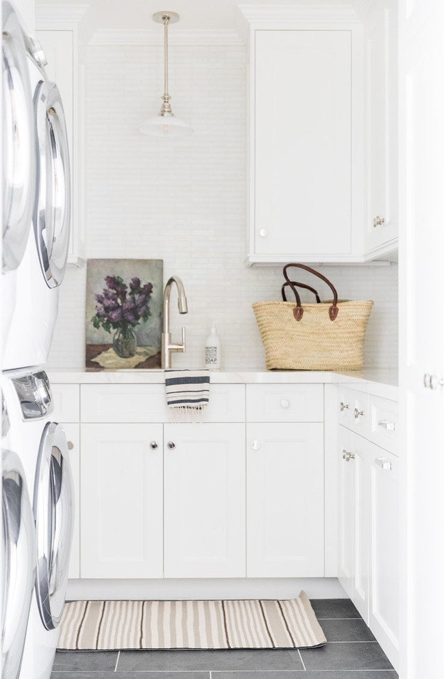 Design ideas for a small nautical l-shaped separated utility room in Salt Lake City with marble worktops, white walls, a stacked washer and dryer, grey floors, white worktops, a submerged sink, shaker cabinets and white cabinets.