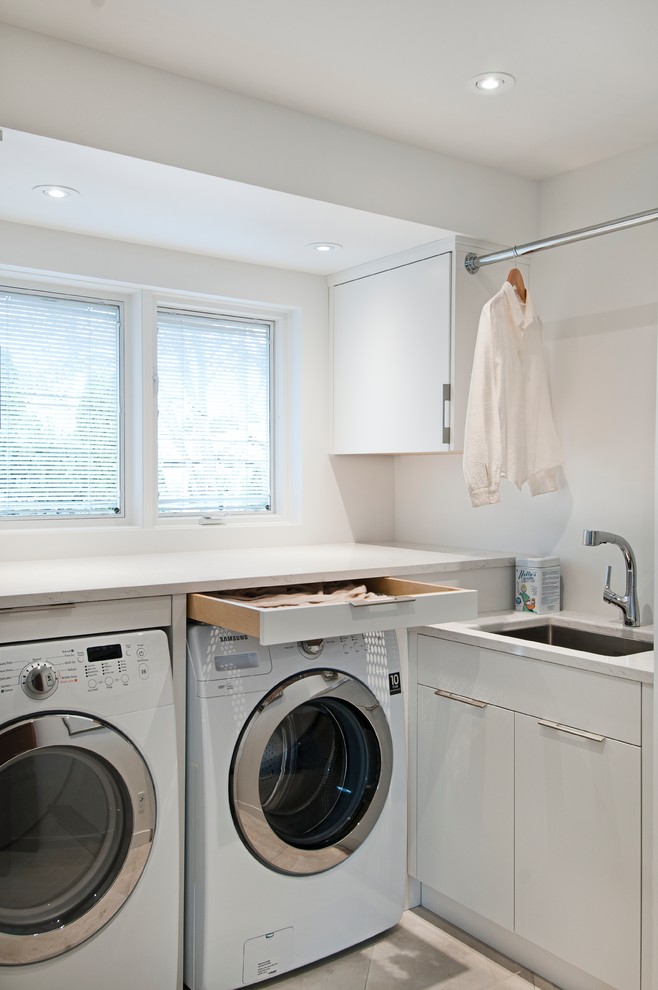 Small contemporary utility room in Vancouver with a submerged sink, flat-panel cabinets, white cabinets, engineered stone countertops, white walls, ceramic flooring and a side by side washer and dryer.