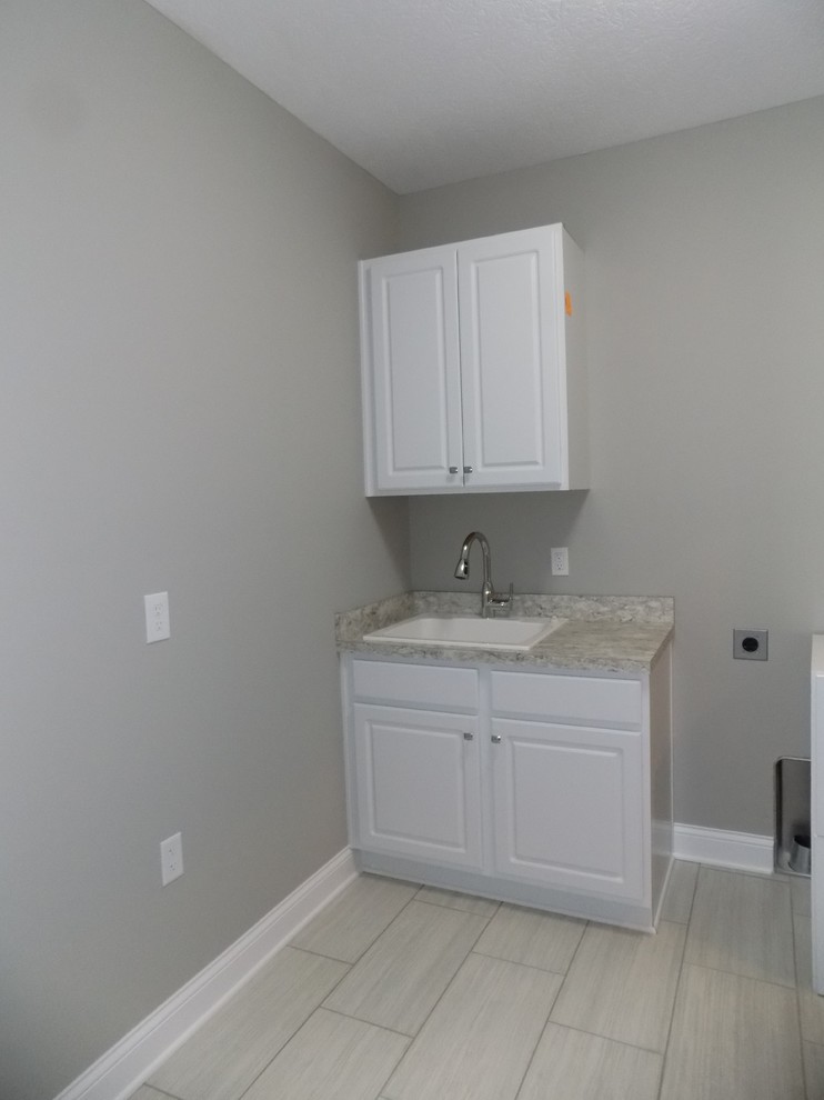 Dedicated laundry room - mid-sized contemporary u-shaped ceramic tile dedicated laundry room idea in Columbus with a drop-in sink, recessed-panel cabinets, white cabinets, laminate countertops, gray walls and a side-by-side washer/dryer