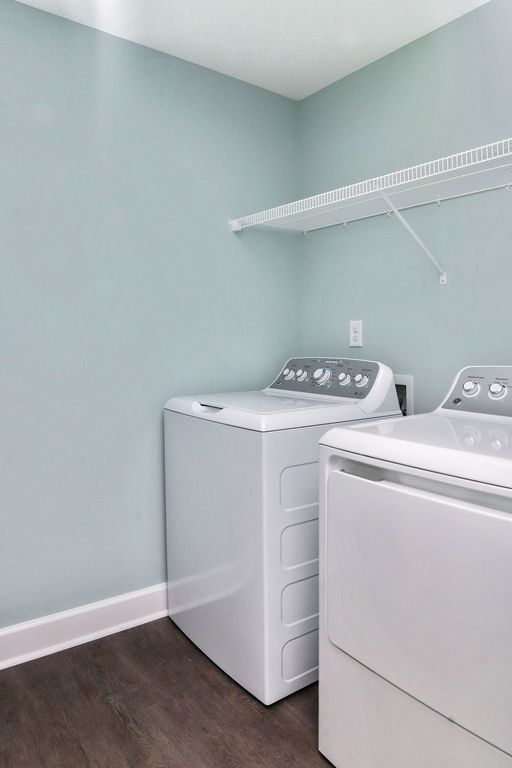 Modelo de cuarto de lavado lineal marinero de tamaño medio con paredes azules, suelo de madera en tonos medios, lavadora y secadora juntas y suelo marrón