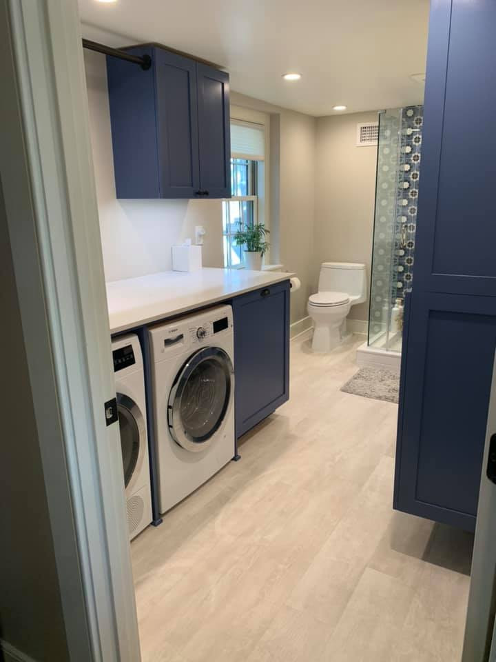 Idee per una lavanderia multiuso vittoriana di medie dimensioni con ante a filo, ante blu, pareti grigie, pavimento in laminato, lavatrice e asciugatrice affiancate, pavimento grigio e top bianco