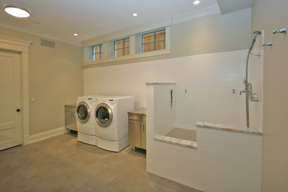 Design ideas for a large classic single-wall utility room in Chicago with flat-panel cabinets, grey cabinets, stainless steel worktops, grey walls, ceramic flooring and a side by side washer and dryer.