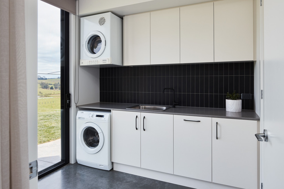 Design ideas for a contemporary galley utility room in Melbourne with a built-in sink and a stacked washer and dryer.