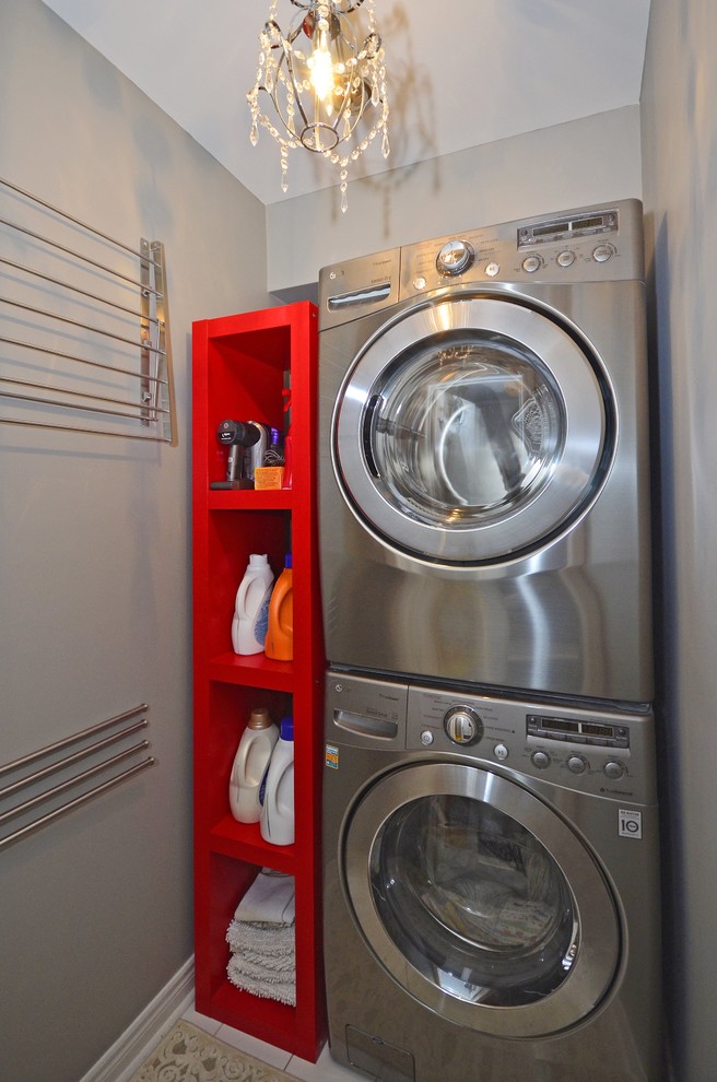 Imagen de lavadero clásico renovado pequeño con lavadora y secadora apiladas y paredes grises
