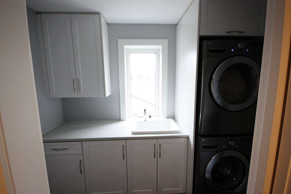 Bild på en mellanstor funkis linjär tvättstuga enbart för tvätt, med en nedsänkt diskho, luckor med infälld panel, vita skåp, laminatbänkskiva, grå väggar, klinkergolv i porslin och en tvättpelare